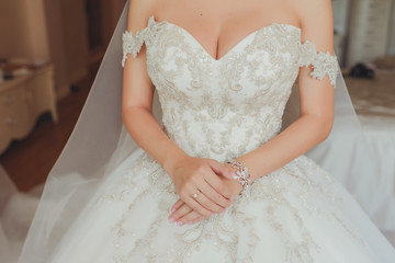 Руки невесты на дорогом пышном свадебном платье с вышивкой