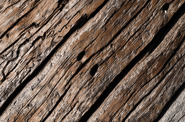 The texture is an old gray, rotted wooden board with deep wavy cracks and holes.