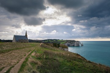 Fototapeta na wymiar The chapel Notre-Dame de la Garde and the limestone cliffs of Etretat with a view of the sea in October, France