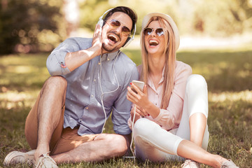 Loving young couple in summer park listening music.