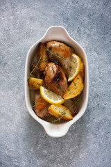 Chicken drumsticks baked with potatoes , lemon and herbs
