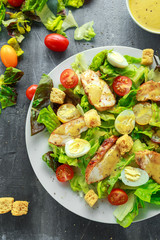 Fresh healthy Caesar salad with chicken, egg quail, tomatoes, Cheese and Croutons in a white plate
