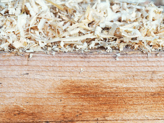 Wood sawdust and shavings on a wide board, carpentry background. Side view