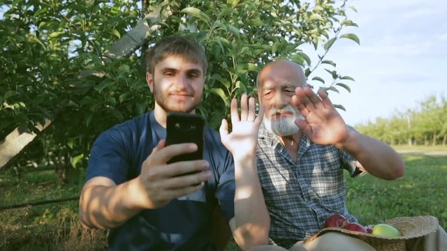 Appearance in the village of good quality Internet. A grandson with a grandfather speaks through a video call using a smartphone