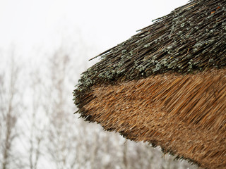 Corner of the old thatched roof, Ukrainian hut architecture. fragment old log house under the straw-thatched roof