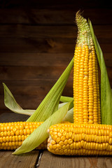 Ripe yellow sweet corn cob on a wooden table close-up