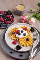 Homemade belgian waffles, gray ceramic cup of coffee and berries