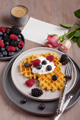 Homemade belgian waffles, gray ceramic cup of coffee and berries