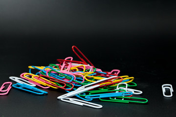 pile of different color paper clip on black background