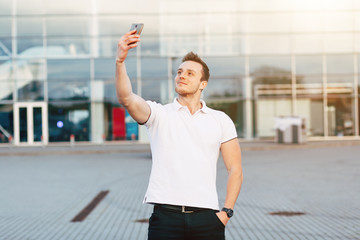 Handsome young man in white T-shirt using smartphone on Airport Parking