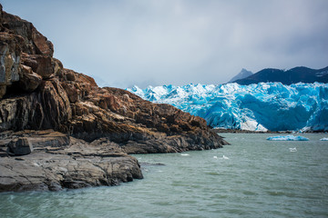 Fototapeta na wymiar A blue glacier near a rocky shore. Shevelev.