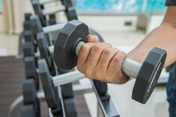 hand of sport man is holding dumbbell, exercising working out at the gym or fitness.