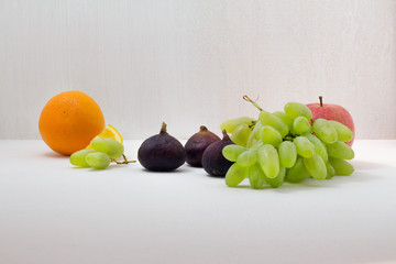 Ripe Grapes, Figs, orange on white wooden table