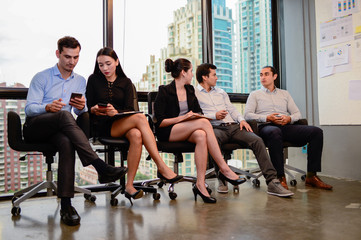 businessman and businesswoman relax sit on chair and hold phone at window in the office