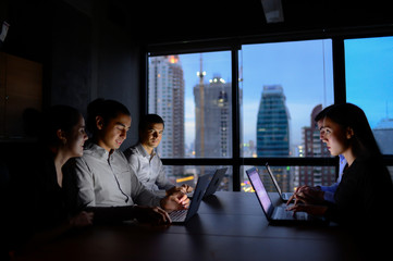 business man and business woman working with computer overtime at night and low light in the office