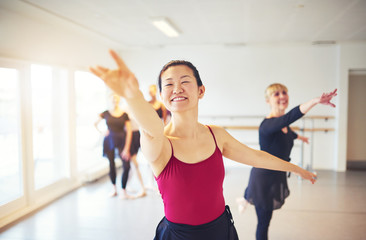 Fototapeta na wymiar Smiling dance teacher leading seniors in a ballet class