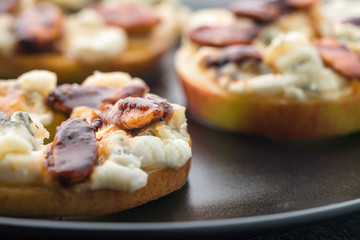 Apple circles with cream cheese, gorgonzola and spicy almond nuts with honey. Dark background