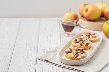 Apple circles with cream cheese, gorgonzola and spicy almond nuts with honey. Rustic white wooden table. Copy space - obrazy, fototapety, plakaty