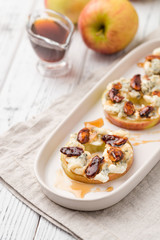 Apple circles with cream cheese, gorgonzola and spicy almond nuts with honey. Rustic white wooden table