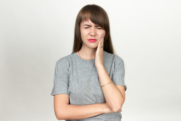 Fototapeta premium Portrait of a pretty woman having toothache standing over gray background
