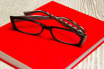 Glasses on a red notepad. Close-up.