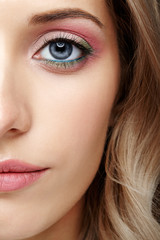 Female half face with pink and green blue eyes makeup