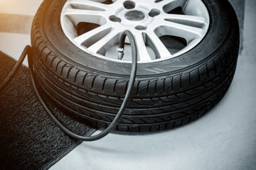 Filling air into a car tire - black and white and sunlight filter effect.