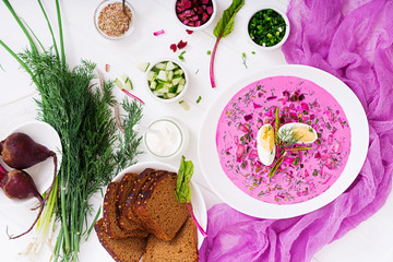 Cold beetroot (beet) soup on yogurt with egg, onion and cucumbers. Flat lay. Top view.
