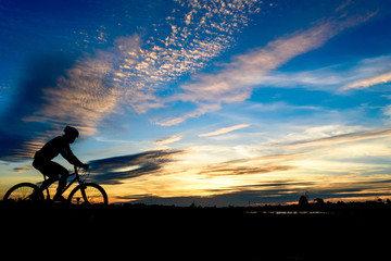 Silhouette of cyclist in motion on the background of beautiful sunset,ride bicycle on sunset background,Silhouette of man ride a bike in sunset background.