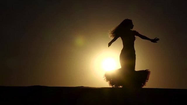 Girl dancer dances gracefully against the background of a hot sunset. Silhouette. Slow motion