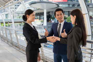 Fototapeta premium business man show thumb up and two business woman shaking hands for demonstrating their agreement to sign agreement or contract between their firms, companies, enterprises. success concept