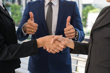 business man show thumb up and two business woman shaking hands for demonstrating their agreement...