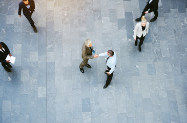 Businessmen shaking hands in the lobby of a busy office