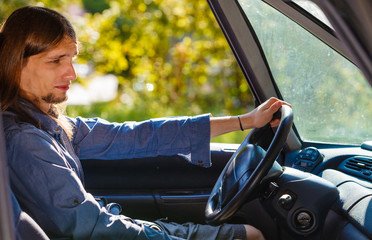 Young man with long hair driving car