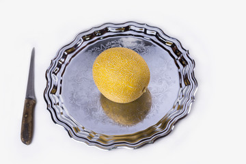 Yellow melon or cantaloupe on the old tray on the white background with knife