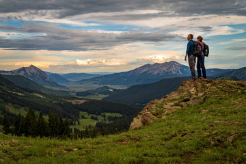Hikers looking down on Crested Butte at sunset - obrazy, fototapety, plakaty