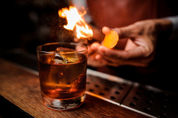The bartender makes flame above cocktail close up