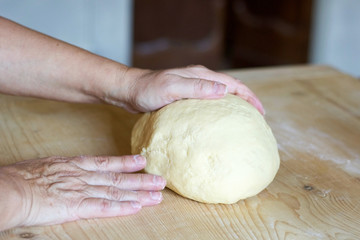 woman's hands on dough for egg pasta
