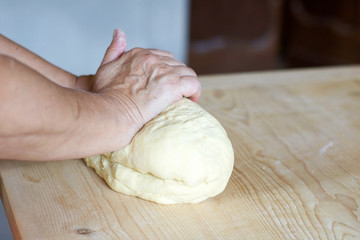 woman's hands kneading bread on a wooden surface