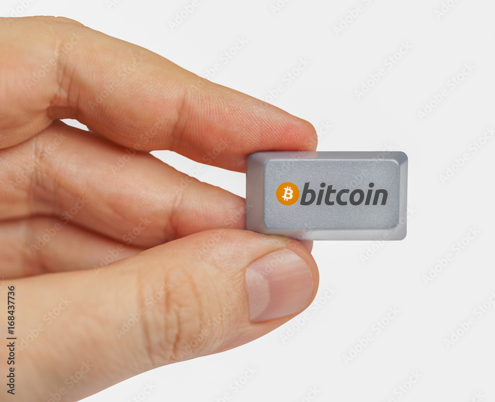 Wall mural hand holding computer key with bitcoin logo. cryptocurrency concept