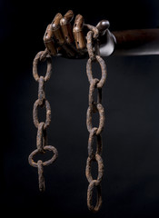 Hand of black man holds a rusty chain. Isolated on dark background. With copy space text. Studio Shot.