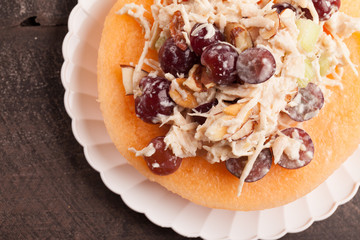 
Cantaloupe ring filled with chicken grape cantaloupe salad on a white plate and dark wooden background horizontal shot

