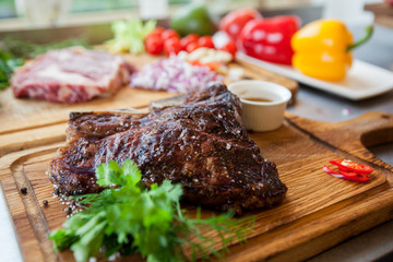 Thick juicy portions of grilled roasted meat on a wooden Board with vegetables