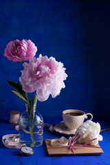 Beautiful pink peonies over the blue background with vintage letters, pocket watch and cup of coffee
