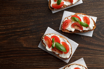 Italian snack bruschetta with cheese, tomato and basil on rustic wooden background.