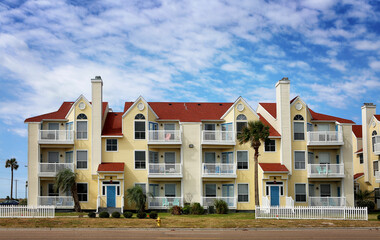 Beautiful modern colorful southern style apartments (condo) with blue sky and plum tries up front.