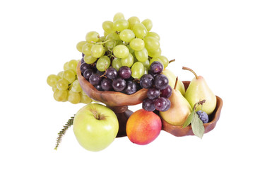 Light and dark grapes in a wooden bowl with an apple pear plum and figs on a white background.Fruit still life