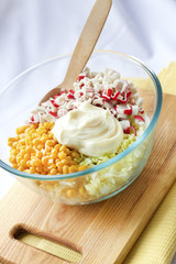 Chinese cabbage, sweet corn, surimi and mayonnaise in a glass bowl