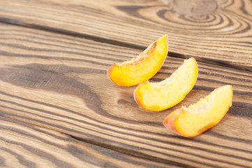 Three slices of fresh ripe peach on rustic old wooden planks