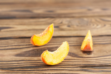 Three slices of fresh ripe peach on rustic old wooden planks